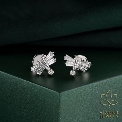 une paire de boucles d'oreilles ornées de diamants, posée sur un écrin vert