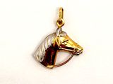 a gold horse head pendant on a white background