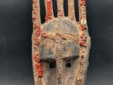 un masque en bois orné de motifs rouges et blancs