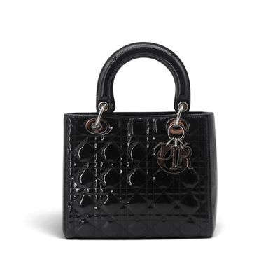 un sac à main noir muni d'une poignée métallique sur fond blanc