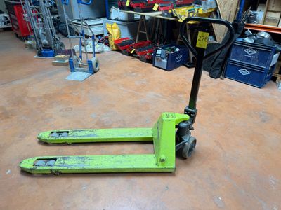 un chariot élévateur vert posé au sol dans un garage