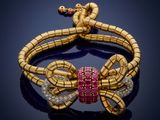 a gold snake bracelet with pink and white diamonds