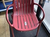 a red plastic chair sitting in front of a glass door