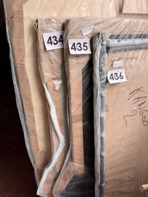 Des cartons contenant des matelas sont empilés les uns sur les autres dans un entrepôt