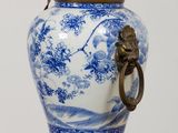 un vase bleu et blanc posé sur une table sur laquelle se trouve une lampe
