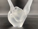 a clear glass bird sitting on top of a black table