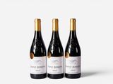 three bottles of wine sit side by side on a white surface