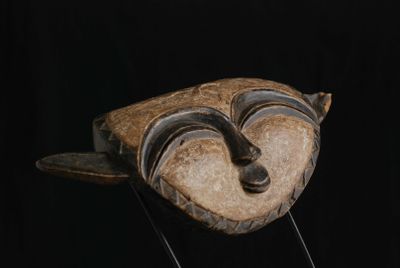 un masque en bois sur un support avec un fond noir
