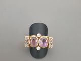 un gros plan d'une bague en or sertie de deux pierres roses