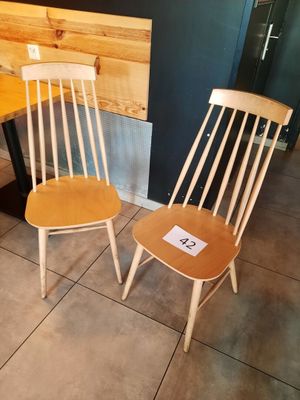 two wooden chairs sitting next to a table in a room