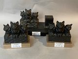 three bronze statues of cats sitting on top of a wooden base