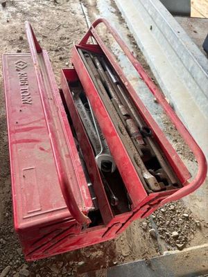 une boîte à outils rouge posée sur une pile d'outils
