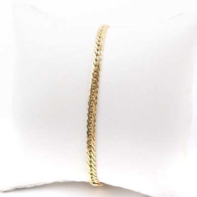 un gros plan d'un bracelet à maillons dorés posé sur un coussin blanc