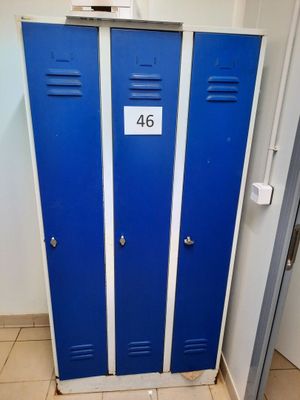 deux casiers bleus dans des toilettes, avec une pancarte sur la porte