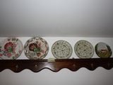 four plates on a shelf with hooks on the wall