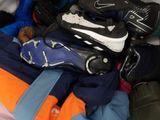 a bag full of clothes and shoes sitting on a bed