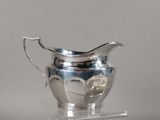 a silver pitcher that is on a clear stand