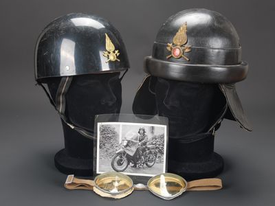 deux casques et des lunettes de protection exposés, accompagnés d'une photo d'un homme à moto