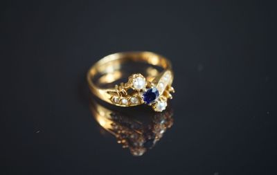 une image montrant un gros plan d'une bague en or posée sur une surface noire