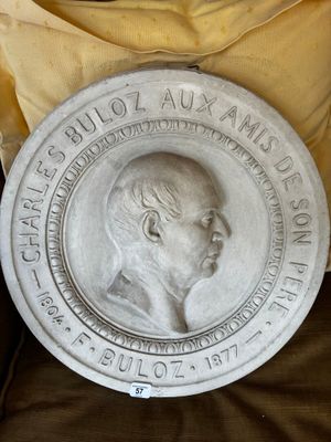 une statue représentant un homme assis sur une chaise à côté d'un oreiller