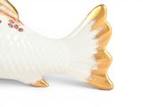 a white and gold fish figurine sitting on a white surface