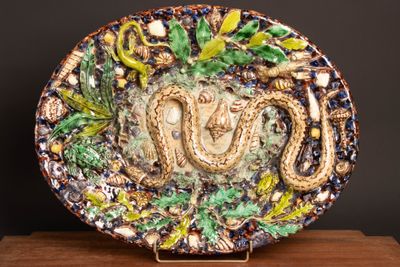 a decorative plate with a snake on it on a wooden stand