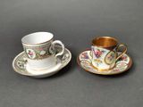 two cups and saucers with gold rims on a table
