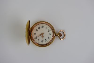 une montre de poche en or sur une surface blanche