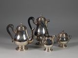 a silver tea set on a table next to other silver items