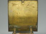 an image of a brass plate on a wooden stand on a gray background