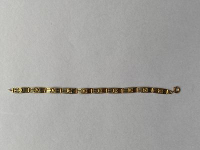 gros plan d'un bracelet en or sur une surface blanche