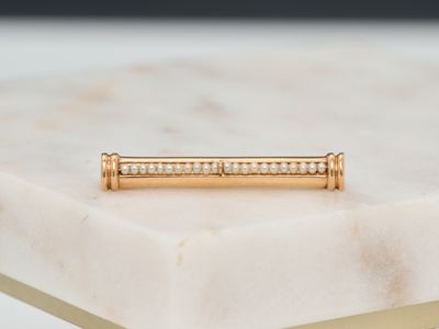 a close up of a gold bar ring on a marble table
