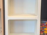 a white book shelf with three shelves next to each other