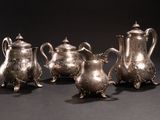 three silver teapots and a coffee pot on a table