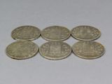 six coins sitting on top of each other on a white surface