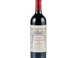 the bottle of red wine is sitting on a white surface