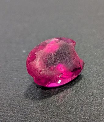 pink diamond on a black surface with water droplets on it