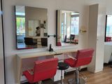 a picture of a salon with red chairs and a large mirror