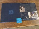 L'album est posé sur une table en bois sur laquelle est collé un autocollant bleu.