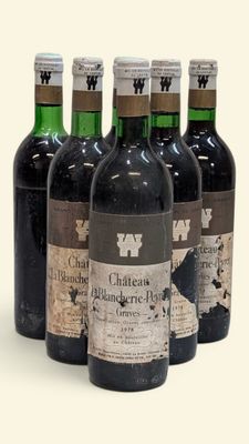 six bouteilles de vin sont alignées sur une surface blanche