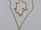 a gold necklace with a black pearl hangs from a gold chain
