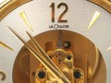 a gold clock with gears inside of it on a white surface