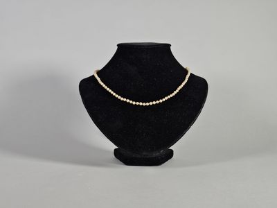 un mannequin noir portant un collier de perles