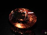 a close up of an orange diamond on a black surface