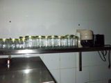 many jars on a shelf in a kitchen with a coffee maker