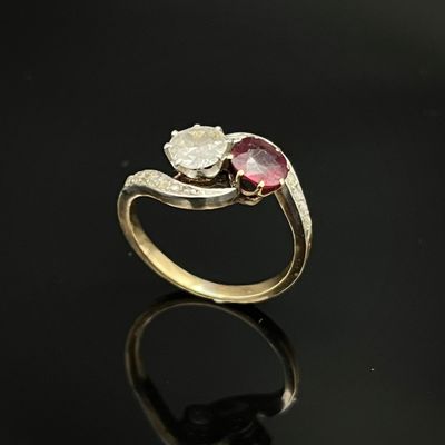 un gros plan d'une bague en or sertie d'une pierre rose et blanche