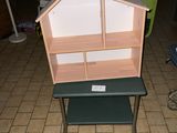 une petite table sur laquelle est posée une maison de poupées