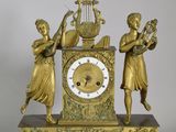 a gold clock with two women playing musical instruments