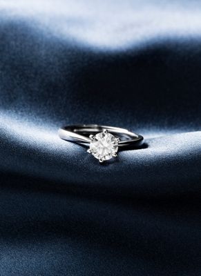 un gros plan d'une bague en diamant sur un fond de satin bleu