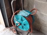 a hose on a cart next to a brick wall